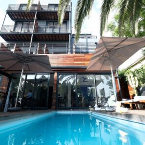 The Tree House Boutique Hotel by The Living Journey Collection: a swimming pool with umbrellas next to a building