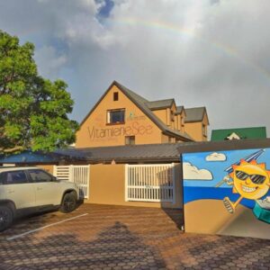 Vitamiene-See Hartenbos: a rainbow over a building with a car parked in front