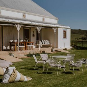 Vleidam Guest Farm: a white house with chairs and a table in the grass