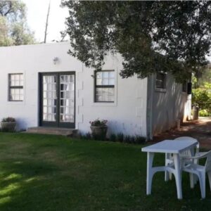 Vredelus Farm Stay Family Cottage: a white house with a table in the yard