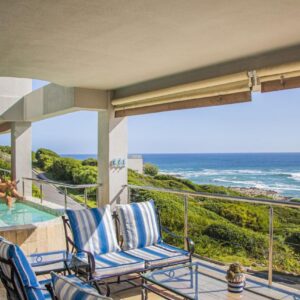 Whale Waters Self Catering Gansbaai: a house with a balcony with two chairs and the ocean