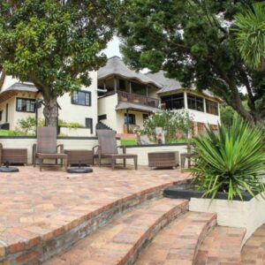 Winelands Villa Guesthouse and Cottages: a house with a patio with chairs and a swimming pool