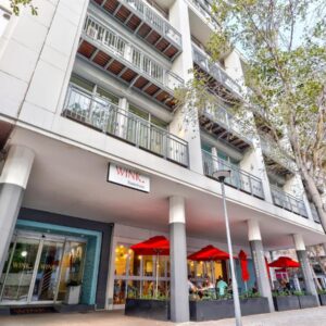 WINK Aparthotel Foreshore: a white building with red umbrellas in front of it